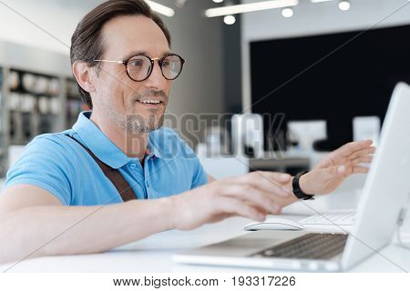 I am quite amazed. Astonished male customer testing a mockup laptop while standing at a display and shopping for new technological devices.