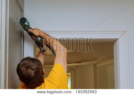Carpenter Brad Using Nail Gun To Moldings On Doors, Framing Trim,