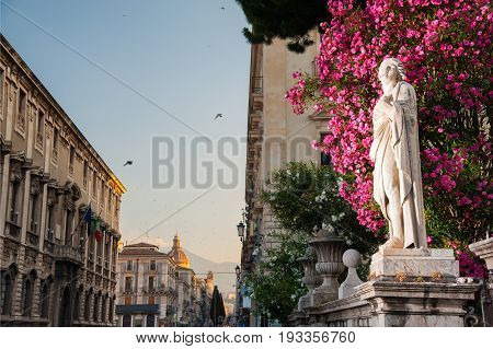 Statue outside the Church of St. Agatha in Catania Sicily with the town and Mount Etna in the background