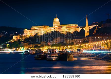 Evening View Of Buda Castle With City Lights And Ship On The Danube River