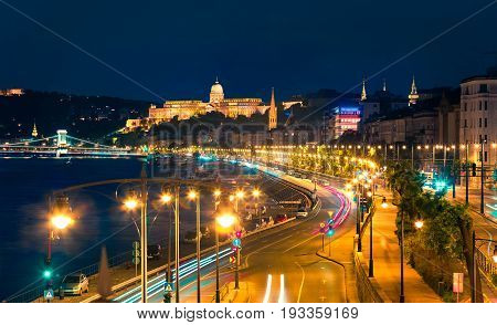 Evening View Of Buda Castle With City Lights And Ship On The Danube River.