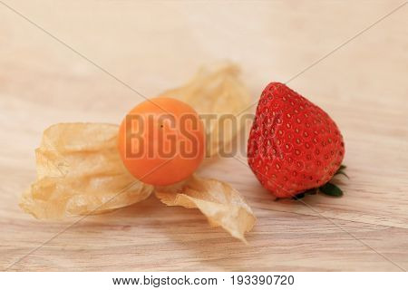Strawberry and Cape gooseberry fruit on wooden background.