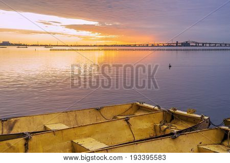 Three Yellow Metal Boats Tied Together On Calm Lake At Dawn Under A Brilliant Gold And Violet Sunris