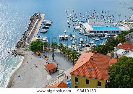 HERCEG NOVI MONTENEGRO - SEPTEMBER 25 2015: View of coast of Herceg Novi and bay from fortress wall Forte Mare Montenegro. Unknown people are resting on beach and by pool