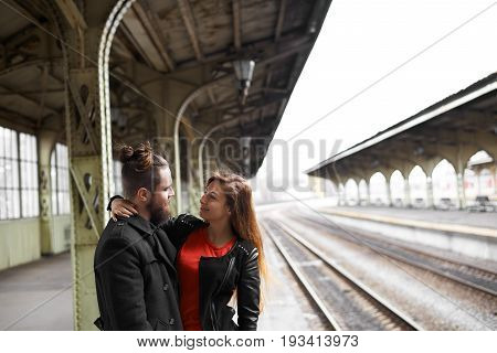 Love and long distance relationships. Beautiful young couple hugging standing on platform at train station happy to see each other after long separation. Cute girl embracing her attractive boyfriend