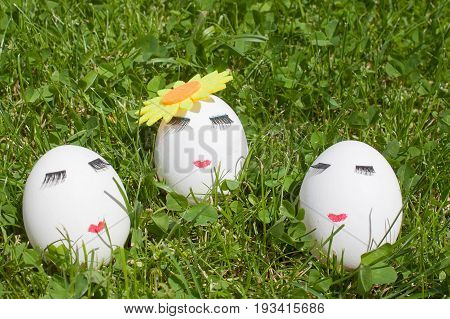 three eggs with make-up on green grass