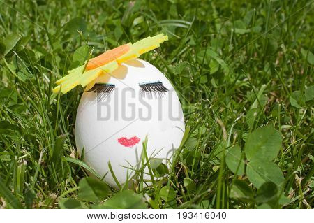 one egg with make-up on green background