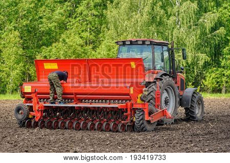Farmer Seeding Crops On Tractor At Field. Russia