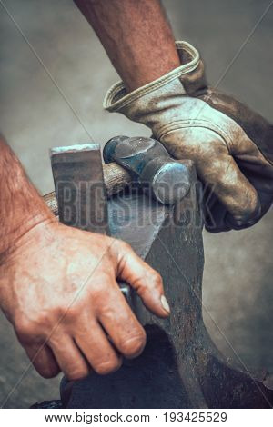 A blacksmith resting his hands on anvil after work at medieval fair festival in Streatham Park in London