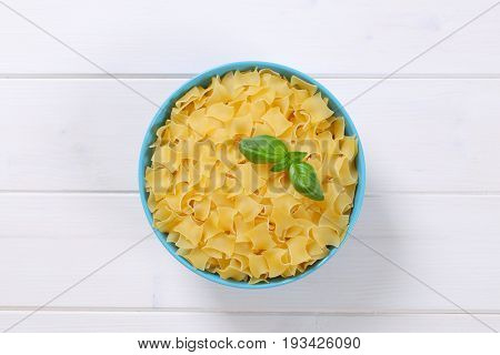 bowl of quadretti - square shaped pasta on white wooden background