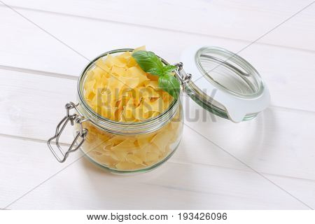 jar of quadretti - square shaped pasta on white wooden background
