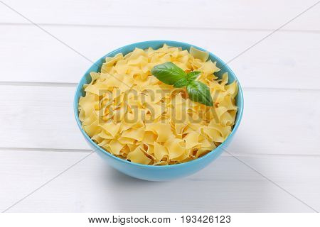 bowl of quadretti - square shaped pasta on white wooden background