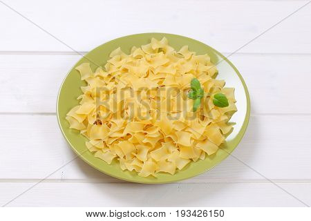 plate of quadretti - square shaped pasta on white wooden background
