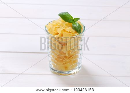 glass of quadretti - square shaped pasta on white wooden background
