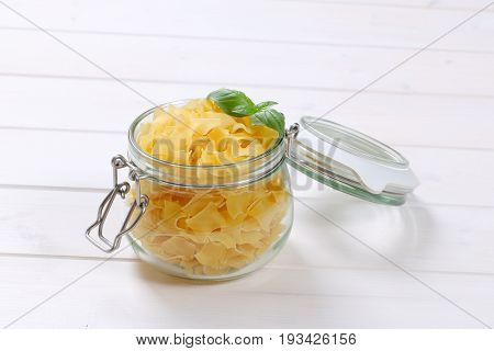 jar of quadretti - square shaped pasta on white wooden background