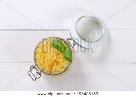 jar of quadretti - square shaped pasta on white wooden background