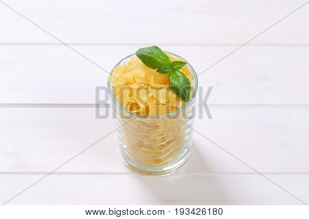 glass of quadretti - square shaped pasta on white wooden background