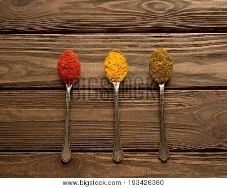 Spice. Spice powder on a wooden background. Three spoons with various spices.