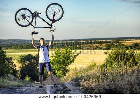 Man holding a road bike over his head with sunset background