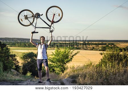 Man holding a road bike over his head with sunset background