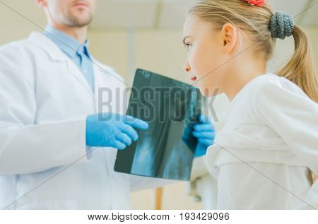 Caucasian Girl Being Examined by Professional Medical Doctor. Reviewing X Ray Imagery.