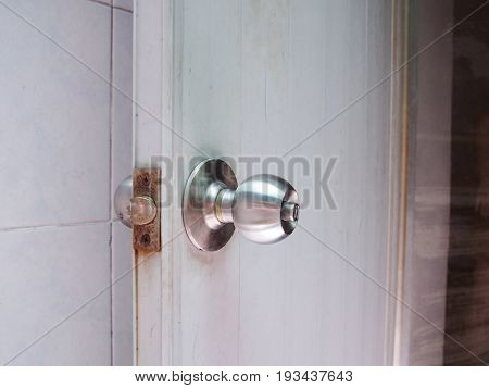 Old rust of stainless steel knob on gray plastic door