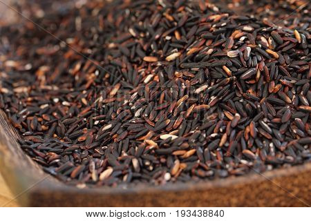 Coarse rice or half polished rice background uncooked raw cereals in bamboo wicker basket shallow depth of field.