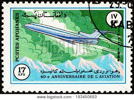 Moscow Russia - April 14 2017: A stamp printed in Afghanistan shows flying passenger airliner over mountains series "40th Anniversary of the ICAO - International Civil Aviation Organization" circa 1984