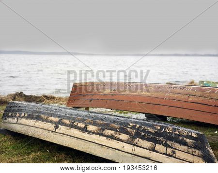 Capsized wooden boats on a lake shore before a storm outdoor cropped photo