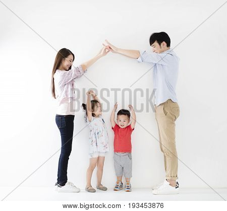happy family making the home sign before white wall