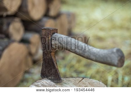 A deck of stacked logs and an axe in a log, the concept of drilling wood