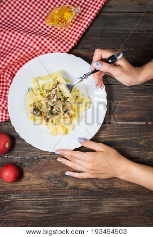 Top View of Woman Eating pasta with Mushrooms on wood table.