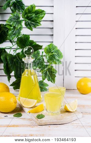 Italian traditional liqueur with lemons on a wooden background. Selective focus.