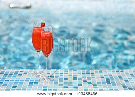 Champagne glasses with strawberry on turquoise background. Rossini cocktail. Summer pool party