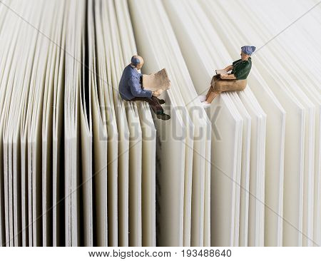 miniature man and woman reading on a book
