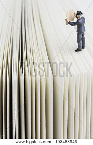 miniature man reading the paper on a book