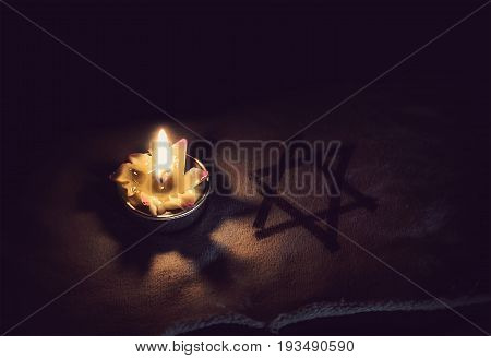 day of memory of victims of the Holocaust burning in the night candle and a symbol of the Jewish star of David