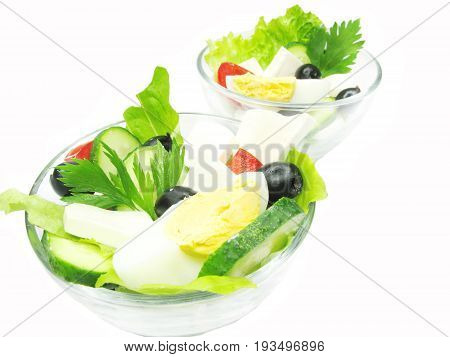 greek salad with cheese egg olive and tomato in two glass bowls