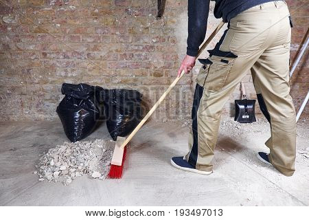 Worker sweeping rubble and dust with broom
