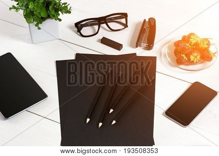 Modern workplace with digital tablet computer and mobile phone, cup of coffee, pen and empty sheet of paper. Top view and copy space for text. sun flare