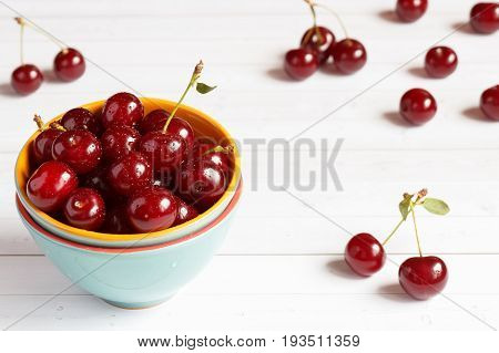 Fresh cherry on plate on wooden background and fresh ripe cherries