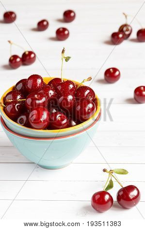 Fresh cherry on plate on wooden background and fresh ripe cherries