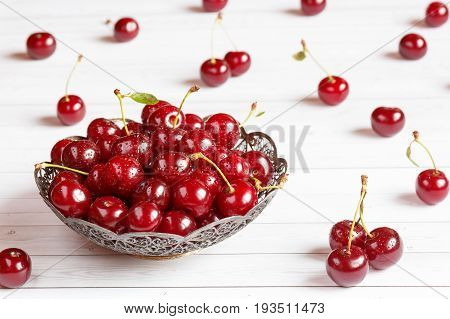 Fresh cherry on plate on wooden background and fresh ripe cherries