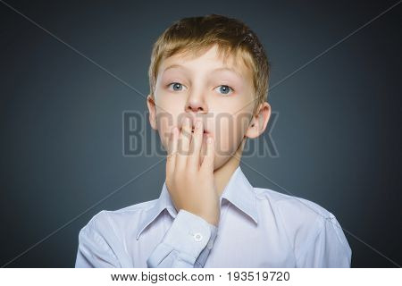 Closeup Portrait of handsome boy with astonished expression while standing against grey background.