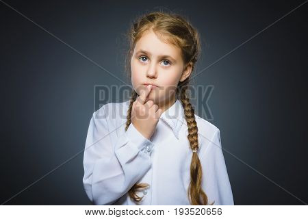 Closeup Thoughtful Young girl Looking Up with Hand on Face isolated on Gray Background.