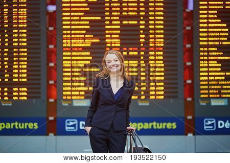 Woman With Hand Luggage In International Airport Terminal, Looking At Information Board