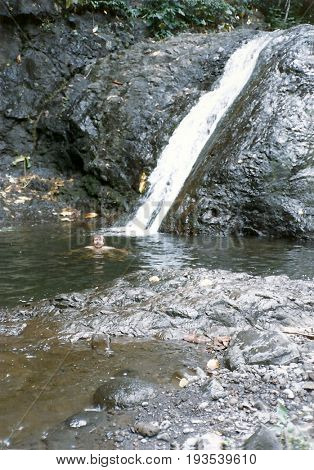 A young man swims in a pool below the Sliding Rocks waterfall on Upolu Island in Samoa.
