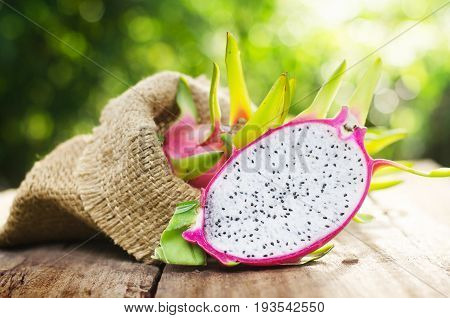 dragon fruit slice on wood table and green nature background with sunlight