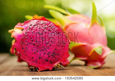 dragon fruit slice on wood table and green nature background with sunlight