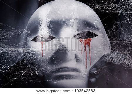 Mysterious woman in black wearing white mask hidden behind spider web,Scary background for book cover